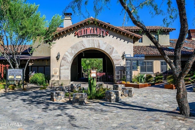 exterior space featuring a chimney, a tile roof, and stucco siding