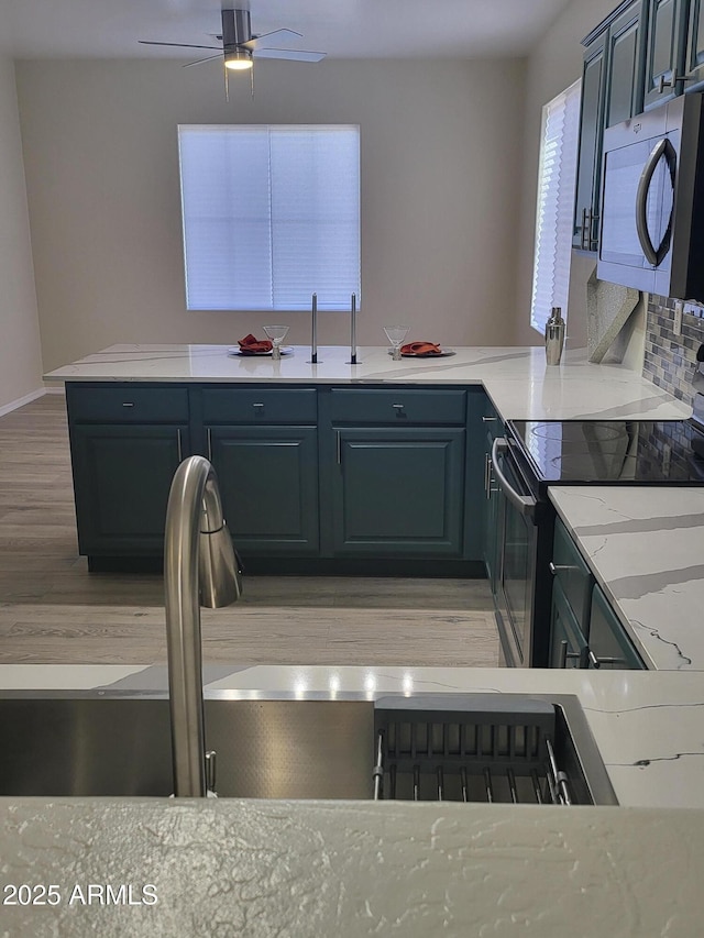 kitchen featuring sink, light stone counters, light hardwood / wood-style flooring, electric range, and ceiling fan