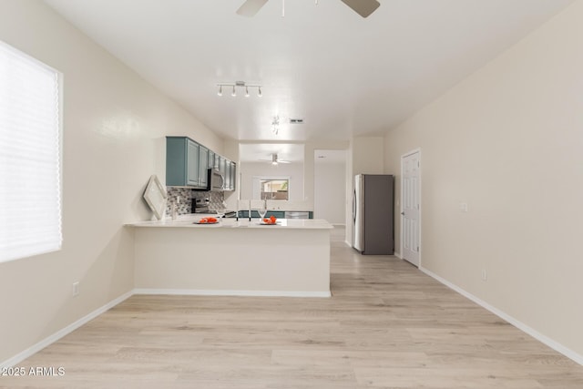 kitchen with light hardwood / wood-style floors, stainless steel appliances, kitchen peninsula, and ceiling fan