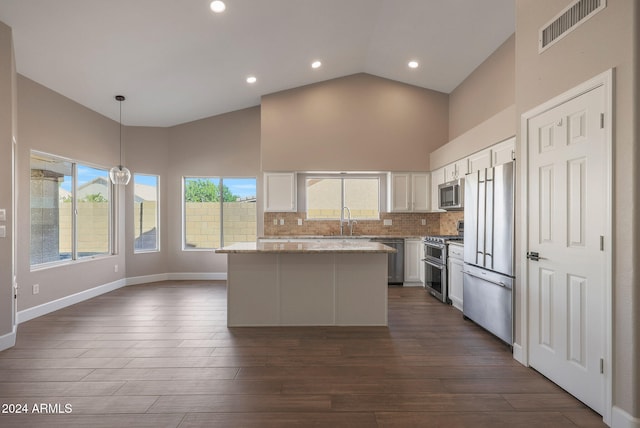 kitchen with high end appliances, white cabinetry, plenty of natural light, and hanging light fixtures