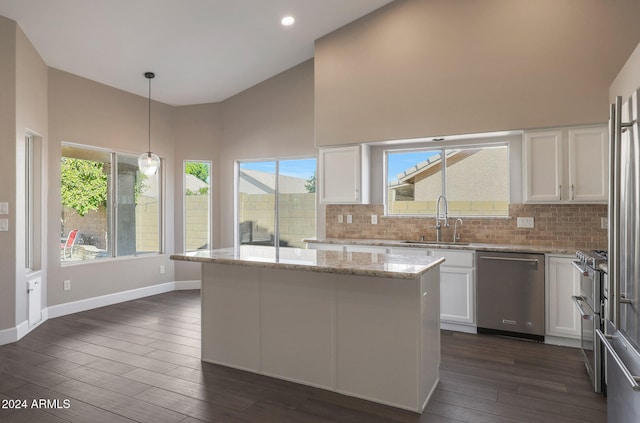 kitchen featuring light stone countertops, decorative light fixtures, stainless steel dishwasher, white cabinets, and dark hardwood / wood-style flooring