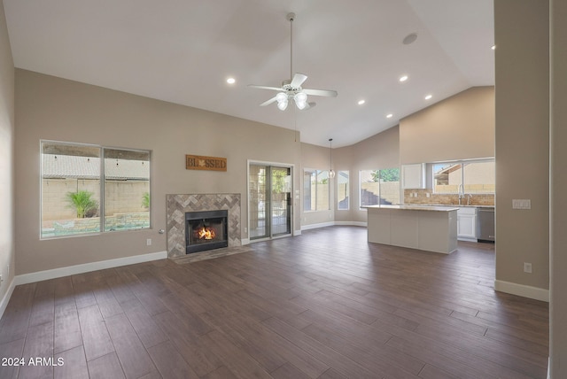 unfurnished living room featuring dark wood-type flooring, a fireplace, high vaulted ceiling, and ceiling fan