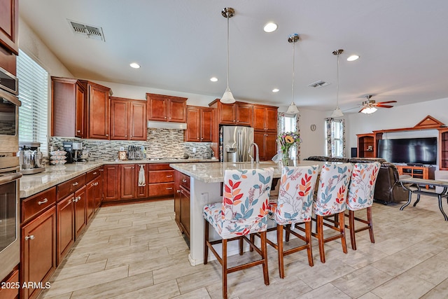 kitchen featuring a kitchen breakfast bar, tasteful backsplash, stainless steel fridge, and visible vents