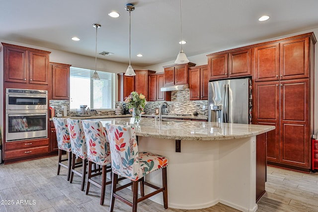 kitchen with a breakfast bar, stainless steel appliances, visible vents, tasteful backsplash, and recessed lighting