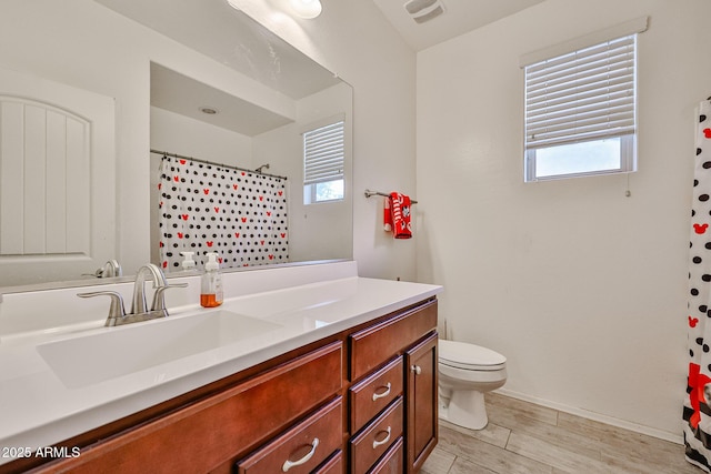 bathroom with toilet, wood finished floors, vanity, curtained shower, and baseboards