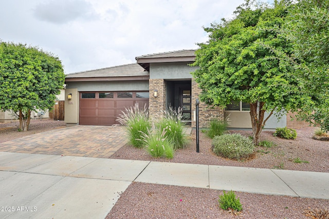 view of front of property featuring a tiled roof, an attached garage, stucco siding, and decorative driveway