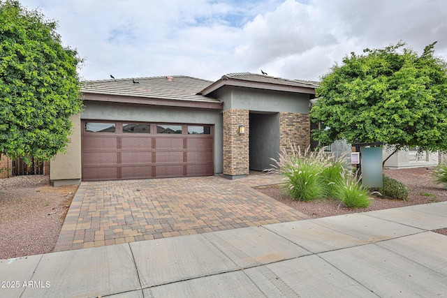 prairie-style house with an attached garage, stucco siding, and decorative driveway