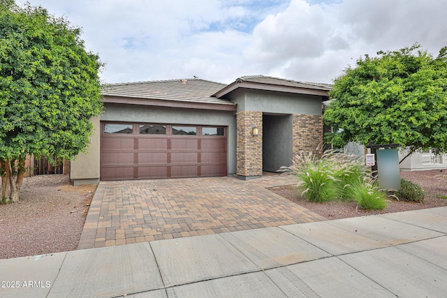 prairie-style home with an attached garage, stucco siding, a tile roof, and decorative driveway