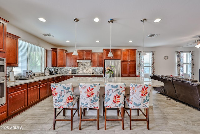 kitchen with a wealth of natural light, stainless steel refrigerator, open floor plan, and a kitchen bar