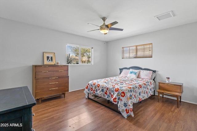 bedroom with wood finished floors, visible vents, and ceiling fan