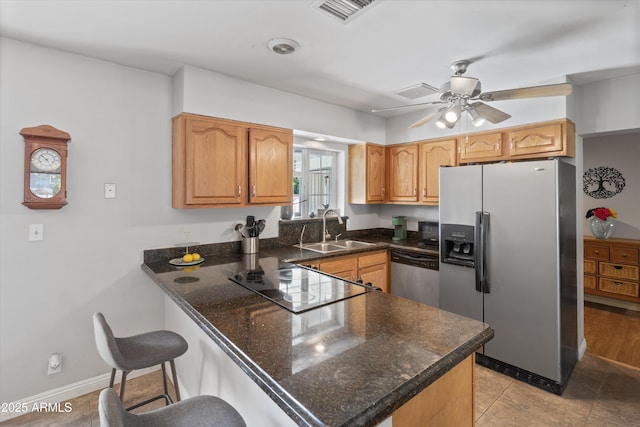 kitchen with stainless steel appliances, visible vents, a sink, a peninsula, and a kitchen bar