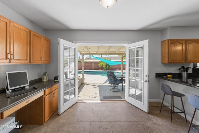 kitchen featuring built in desk, dark countertops, brown cabinetry, and french doors