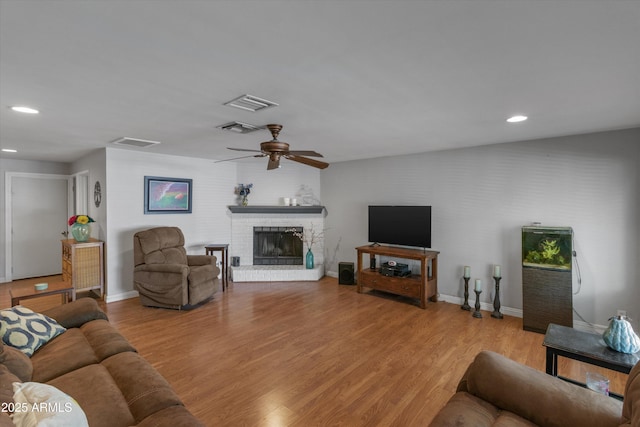 living area featuring baseboards, a ceiling fan, visible vents, and light wood-style flooring