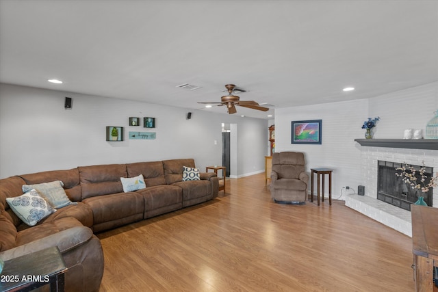 living room with a fireplace, light wood-style flooring, and visible vents