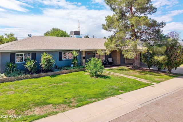 ranch-style home featuring roof with shingles and a front yard
