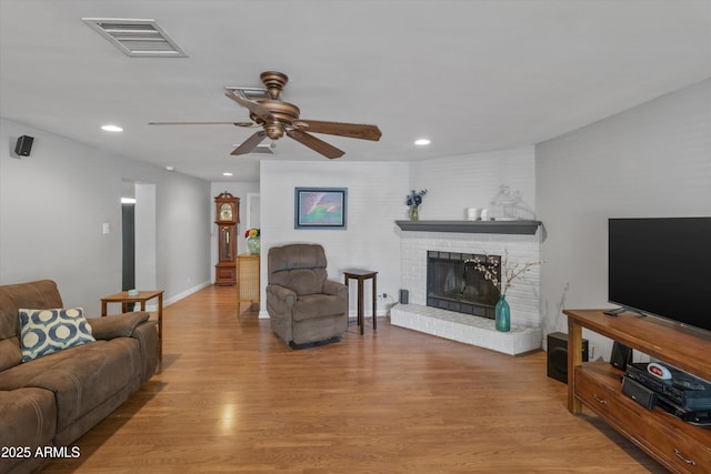 living room with ceiling fan, light wood finished floors, a fireplace, visible vents, and recessed lighting