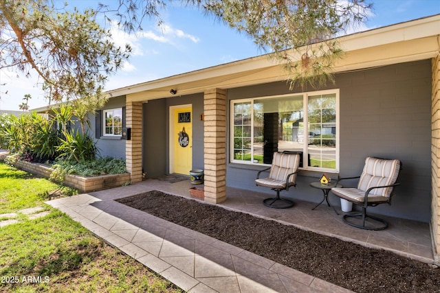 entrance to property featuring a porch and concrete block siding