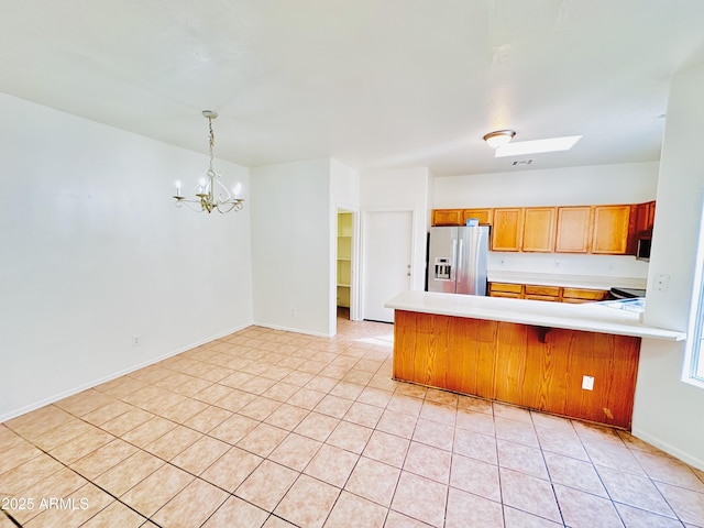 kitchen with stainless steel fridge, a skylight, kitchen peninsula, and a chandelier