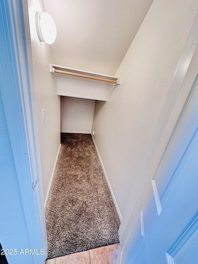 walk in closet with dark colored carpet