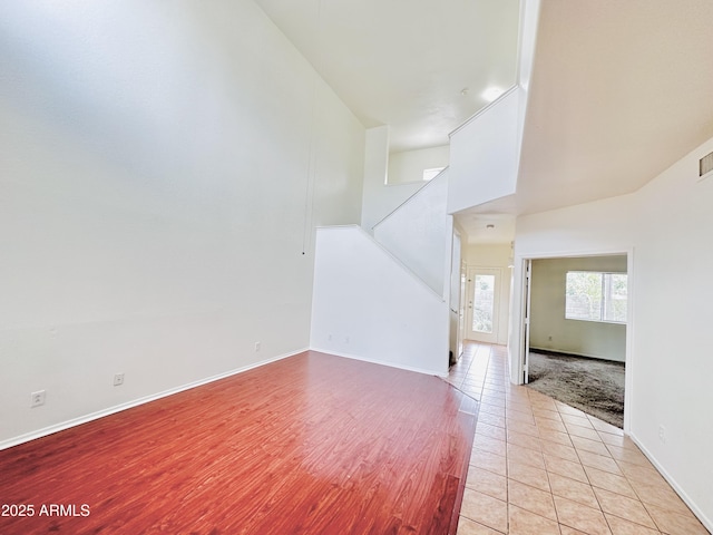 unfurnished living room featuring a high ceiling and light tile patterned flooring