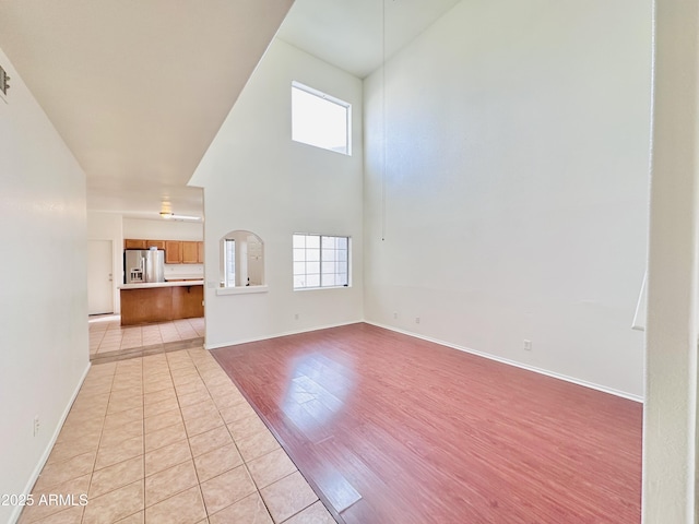 unfurnished living room with light tile patterned floors and a high ceiling