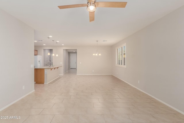 unfurnished living room with ceiling fan with notable chandelier, sink, and light tile patterned floors