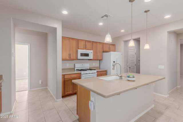 kitchen featuring white appliances, a center island with sink, hanging light fixtures, and sink