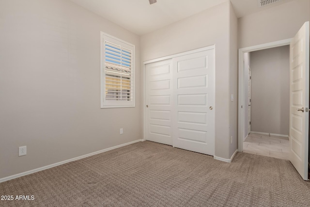 unfurnished bedroom with light colored carpet and a closet