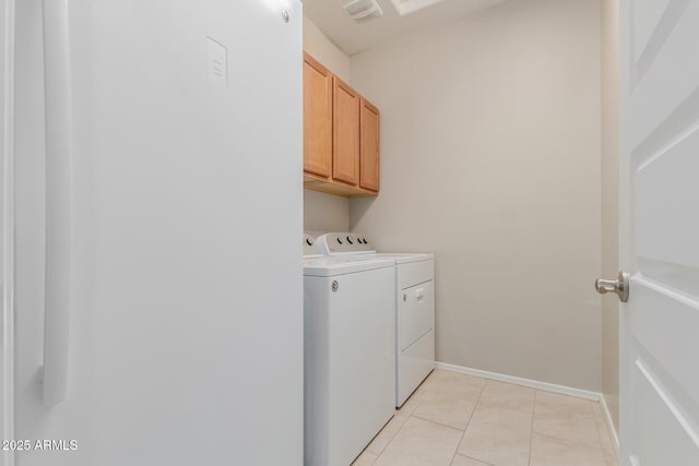 laundry area featuring washing machine and clothes dryer, light tile patterned floors, and cabinets