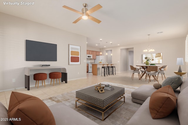 living room with ceiling fan with notable chandelier, light tile patterned floors, and sink