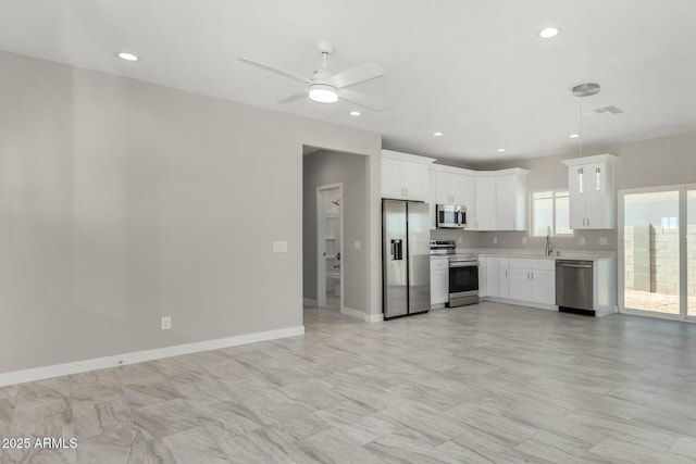 kitchen with light countertops, appliances with stainless steel finishes, white cabinets, a sink, and baseboards