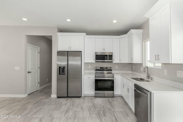 kitchen with recessed lighting, a sink, white cabinets, light countertops, and appliances with stainless steel finishes