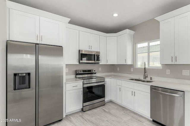 kitchen featuring stainless steel appliances, a sink, light countertops, and white cabinetry