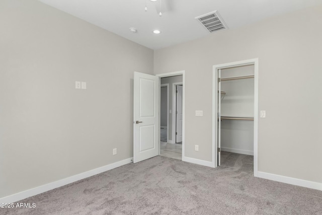 unfurnished bedroom featuring visible vents, baseboards, a closet, carpet, and a walk in closet