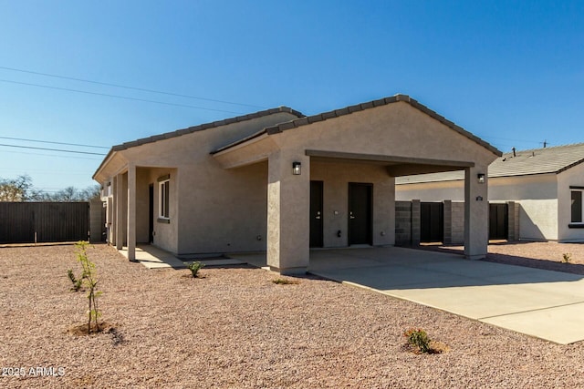 exterior space featuring a tiled roof, fence, and stucco siding