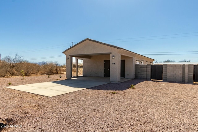 exterior space with a gate, fence, and stucco siding