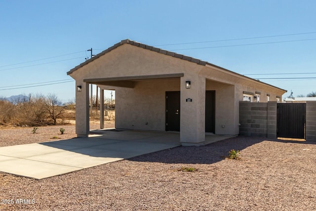 rear view of property with a tile roof, fence, and stucco siding