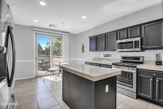 kitchen featuring light stone counters, appliances with stainless steel finishes, light tile patterned floors, and a kitchen island