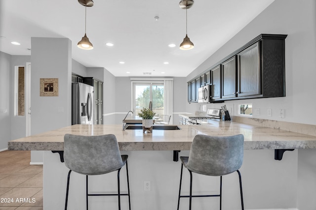 kitchen featuring appliances with stainless steel finishes, kitchen peninsula, a kitchen breakfast bar, and pendant lighting