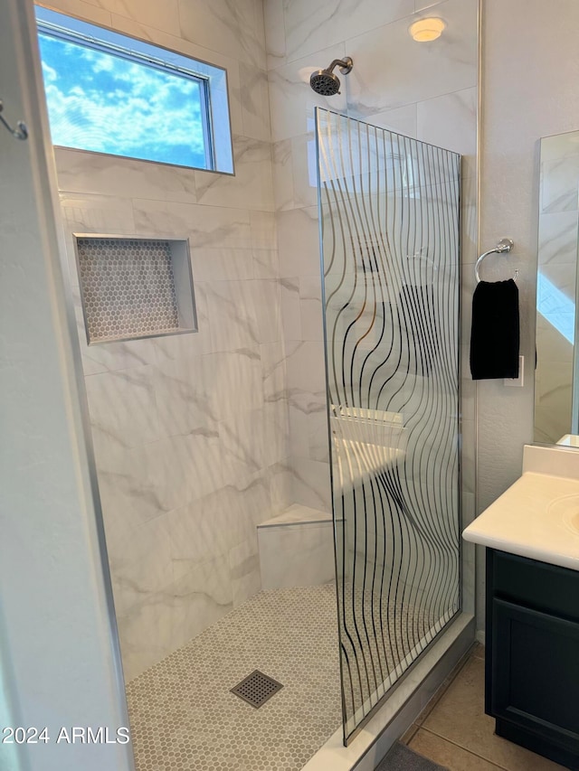 bathroom featuring a tile shower, tile patterned flooring, and vanity