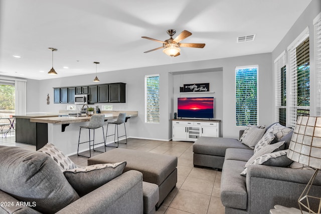 living room featuring ceiling fan, sink, and light tile patterned floors