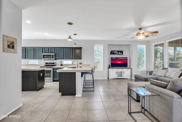 kitchen with pendant lighting, stainless steel appliances, an island with sink, and a healthy amount of sunlight