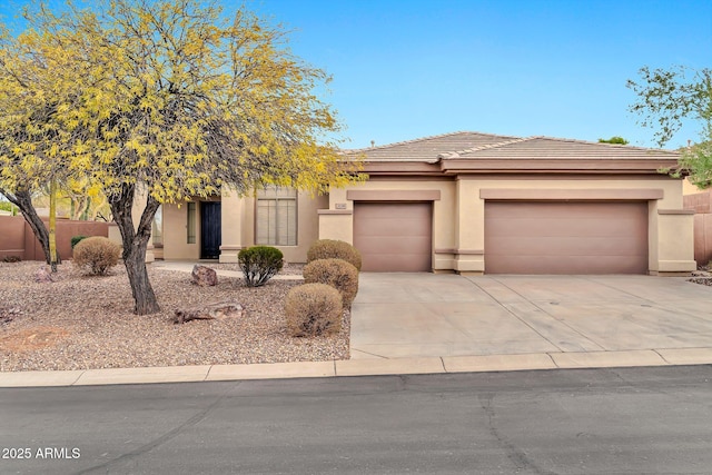 view of front of property featuring an attached garage, a tile roof, concrete driveway, and stucco siding