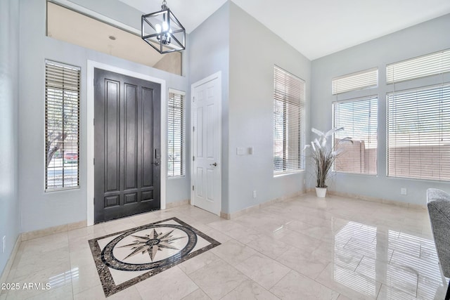 foyer with marble finish floor, baseboards, a wealth of natural light, and an inviting chandelier