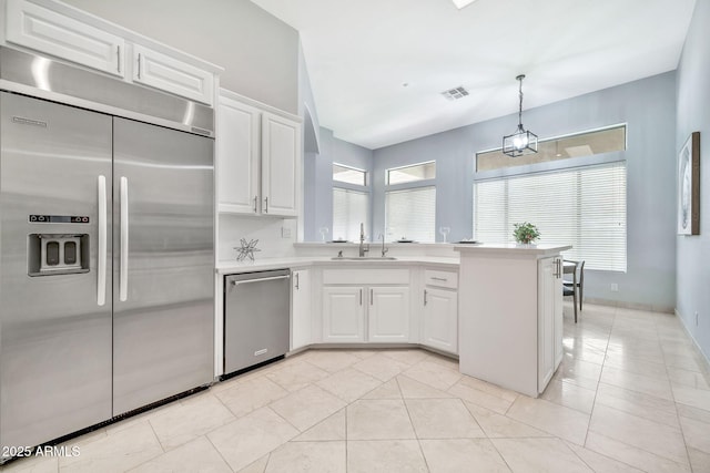 kitchen with light countertops, visible vents, appliances with stainless steel finishes, a sink, and a peninsula