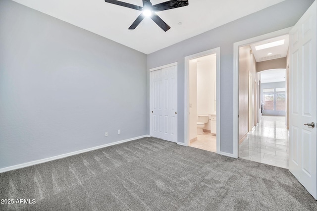 unfurnished bedroom with arched walkways, a closet, a ceiling fan, carpet flooring, and baseboards