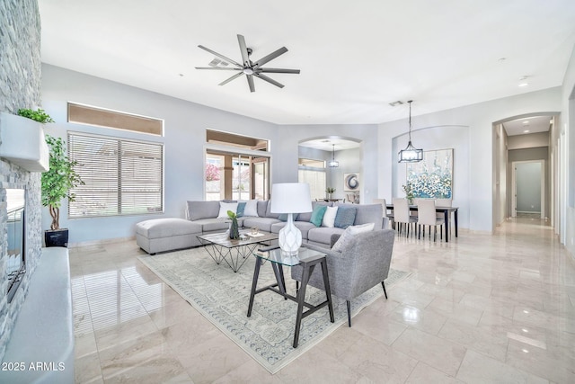 living room with arched walkways, ceiling fan, and a glass covered fireplace