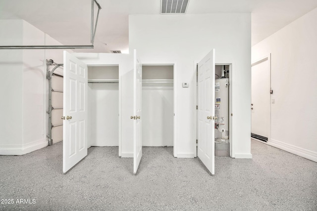 unfurnished bedroom featuring gas water heater, multiple closets, visible vents, baseboards, and speckled floor