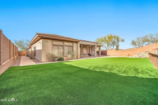 rear view of property with a yard, a patio area, a fenced backyard, and stucco siding