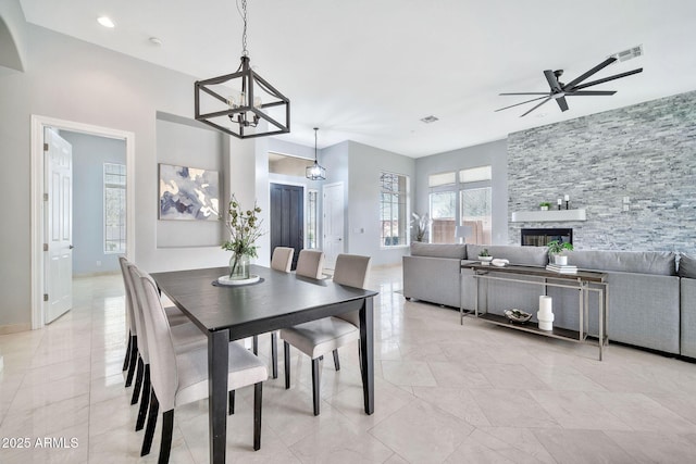 dining space with ceiling fan with notable chandelier, a stone fireplace, visible vents, and recessed lighting